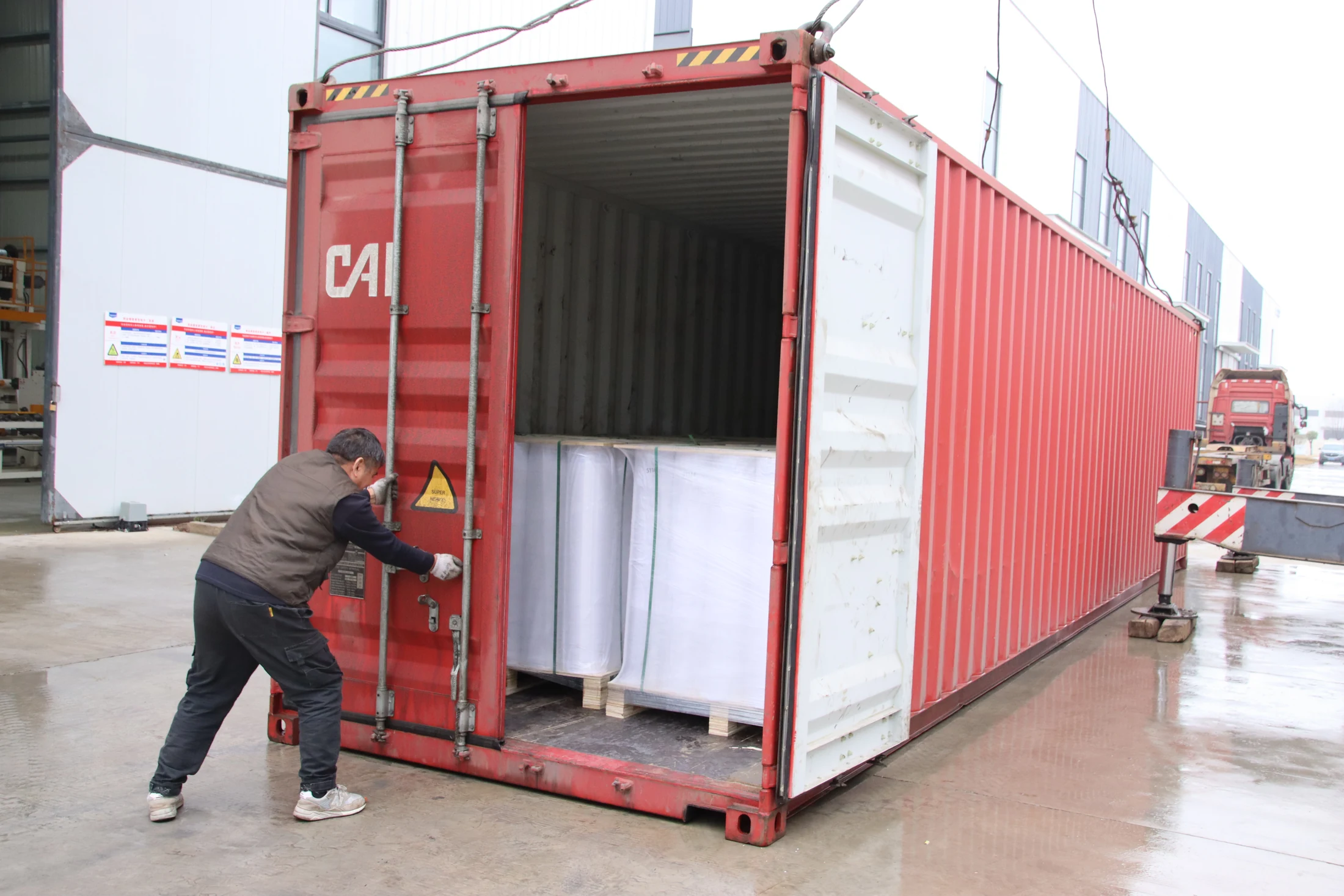 Container being loaded with wrapped membrane rolls